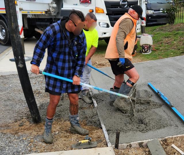 Workers spreading wet concrete on a residential site