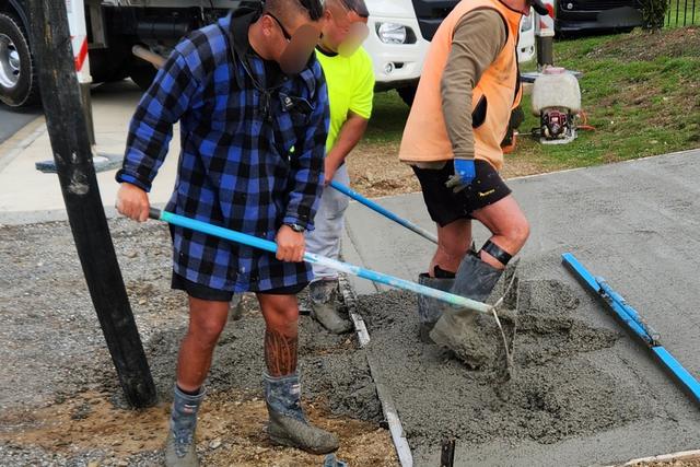 Workers spreading wet concrete on a residential site