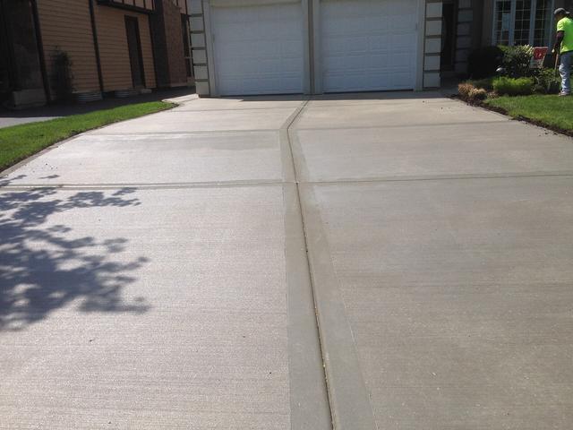 New concrete driveway with saw cut joints leading to a garage