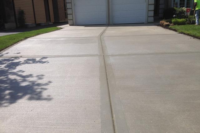New concrete driveway with saw cut joints leading to a garage