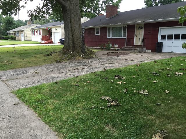 Concrete path running beside a lawn in front of a brick house